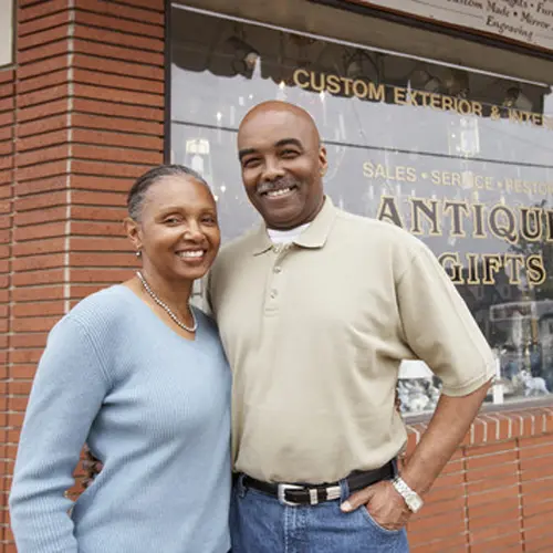 family business owners standing in front of store window