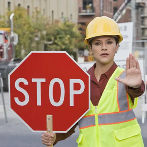 woman holding stop sign in traffic